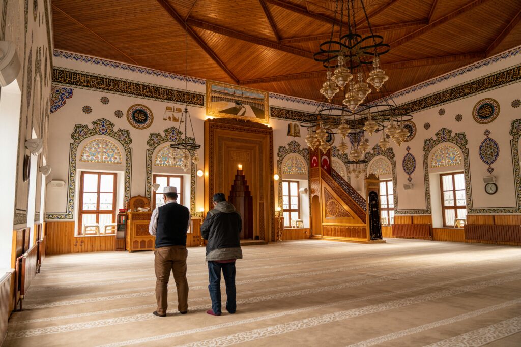 pexels photo 16354013 16354013 Two men praying inside an ornate mosque with stunning architectural details.