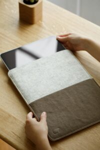 pexels photo 19238504 19238504 Close-up of hands placing a tablet into a modern fabric case on a wooden desk.