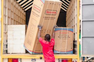 pexels photo 33679977 33679977 A worker in a red shirt loads boxed appliances onto a truck for delivery.
