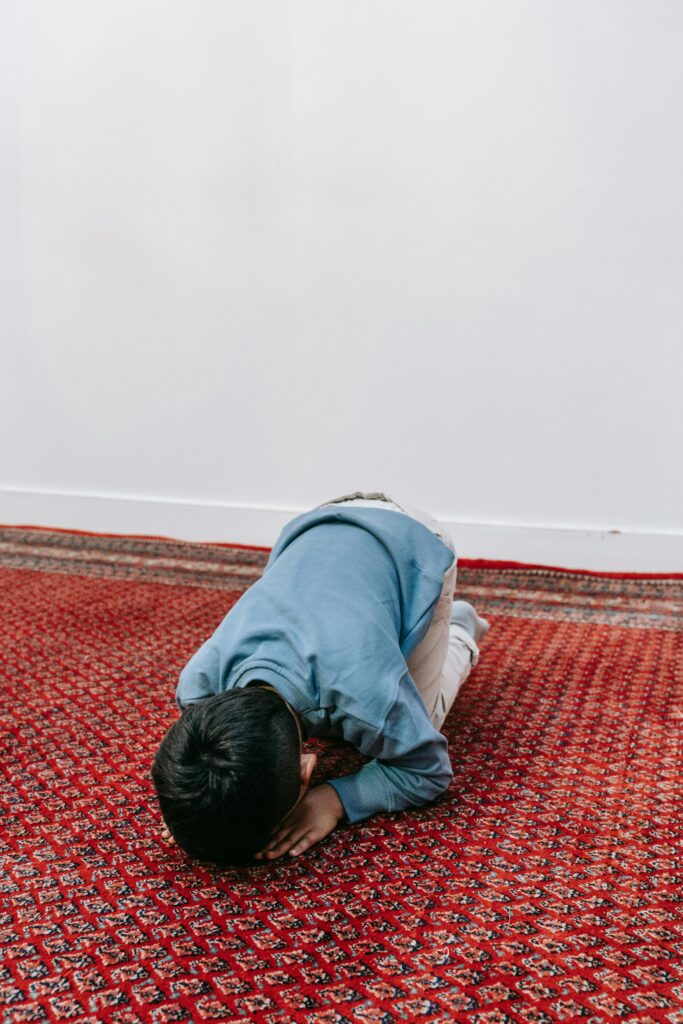 pexels photo 9127654 9127654 Young child kneeling on an intricately designed red carpet in a serene indoor setting.